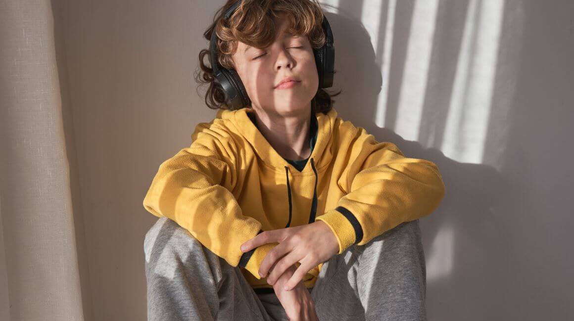 Junge hört auf seinen Kopfhörern einen Podcast
