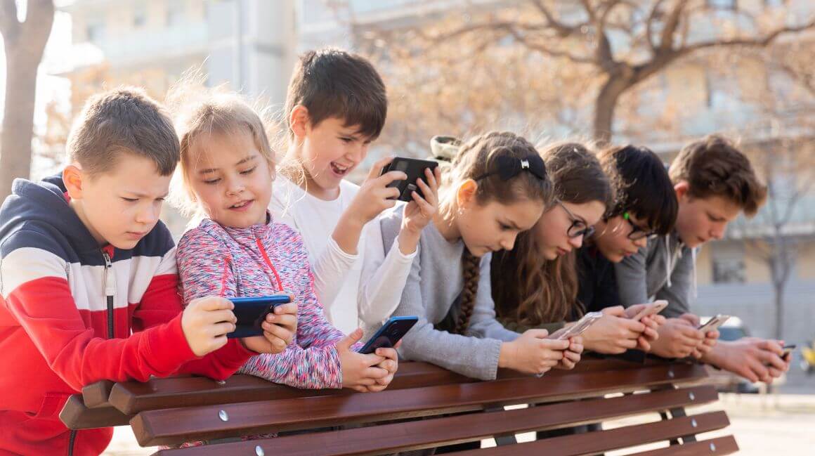 Kinder auf dem Pausenhof schauen alle auf ihr Handy.
