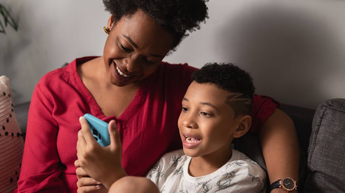 Ein Junge zeigt seiner Mutter auf dem Smartphone etwas.