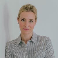 Kathrin-Schmitz-Autorin Porträt einer lächelnden Person mit blonden Haaren, die ein gestreiftes Hemd trägt.