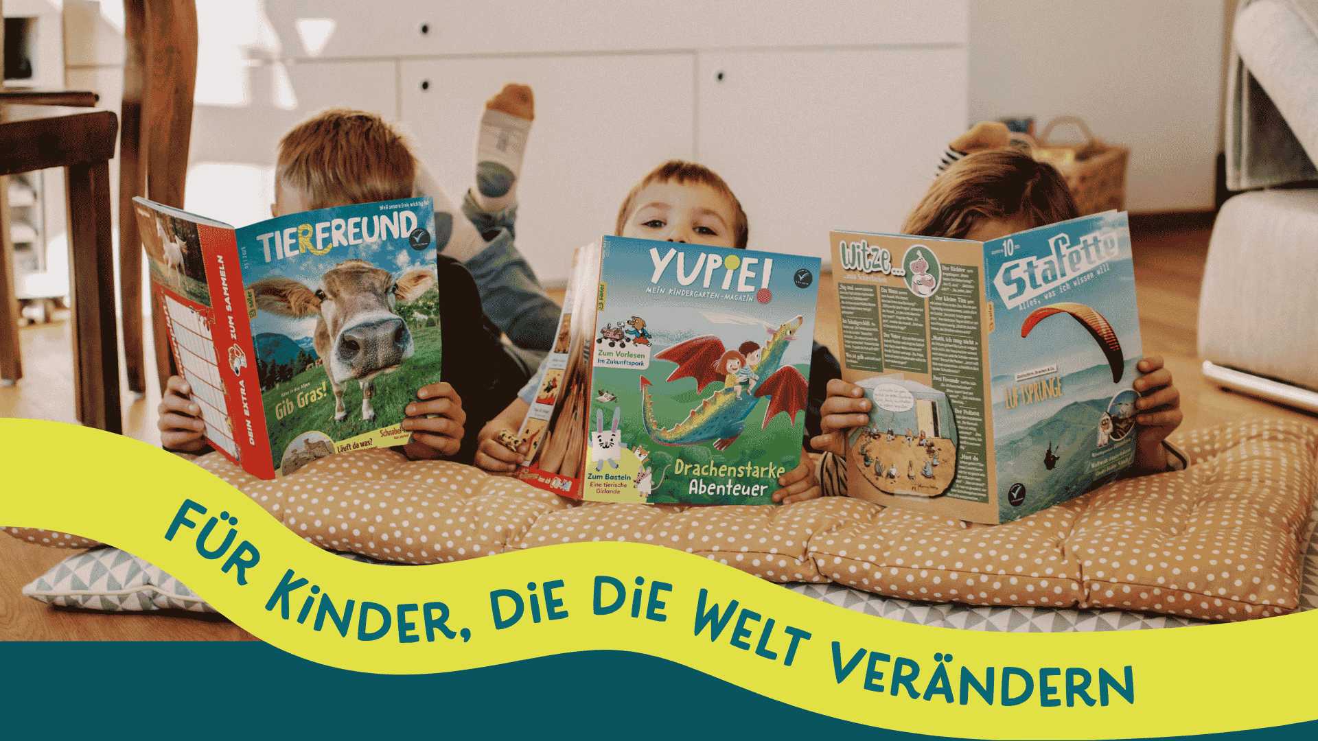 Drei Kinder liegen auf Kissen und lesen Kinderzeitschriften. Die Cover zeigen bunte Illustrationen und Titel wie 'YUPIE!', 'Ulitz' und 'Freund'. Im Vordergrund steht ein Slogan in geschwungener Schrift: 'Für Kinder, die die Welt verändern'.
